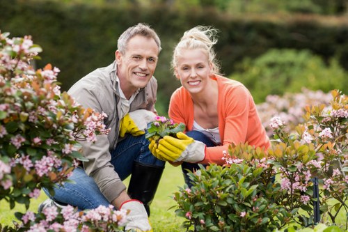 Crew member trimming hedges during a garden maintenance visit